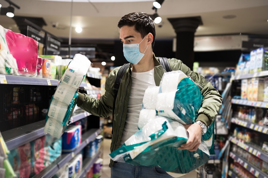 Young man stocking up on toilet paper at a store