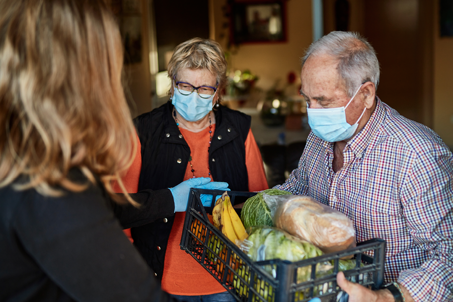 Masked elderly couple receiving home grocery delivery