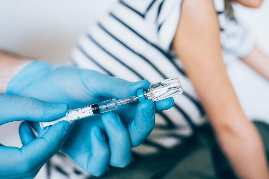 Gloved hands drawing vaccine dose into syringe