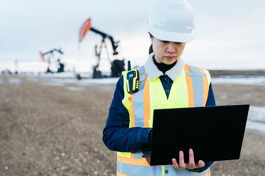Woman working on laptop in oil field