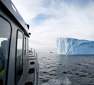 Boat approaching iceberg in ocean