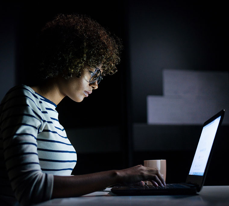 Women in the dark working on their laptop