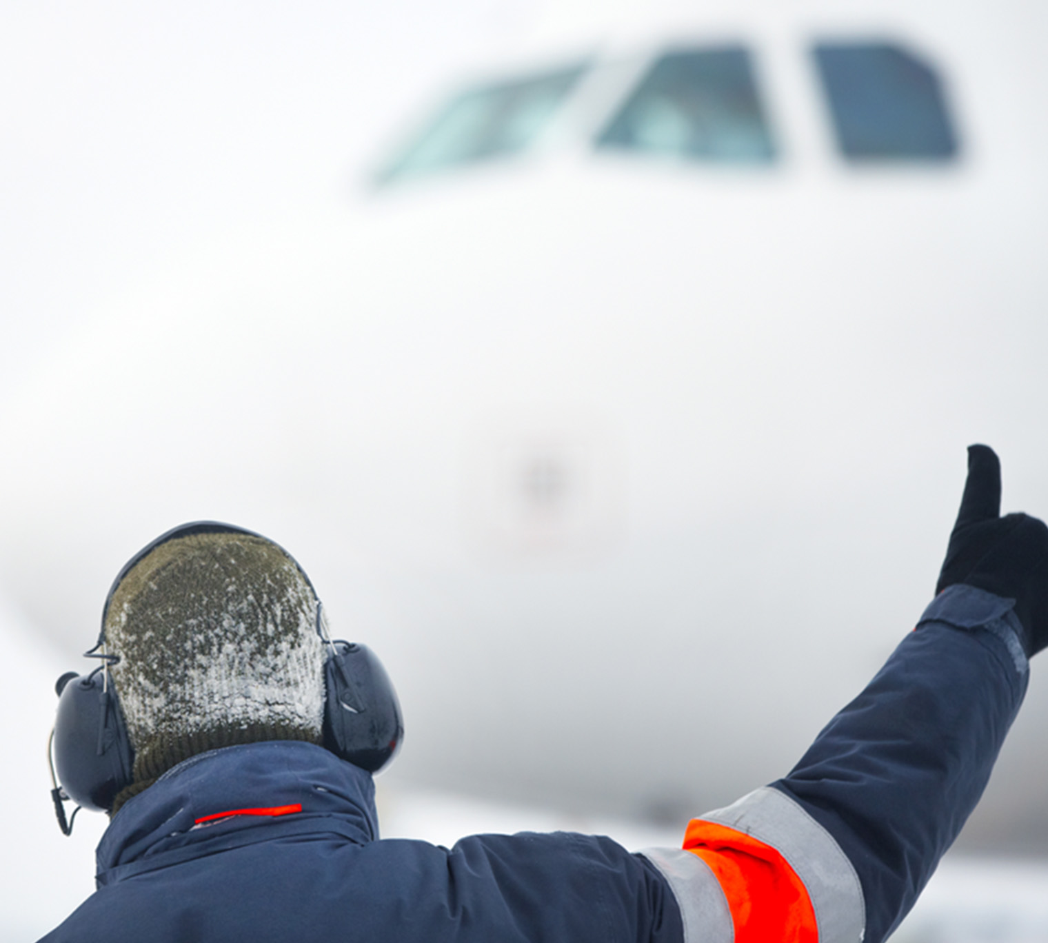 Member of ground crew showing OK sign to airplane pilot