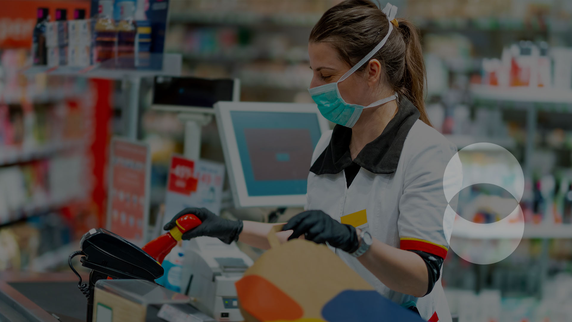 Cashier wearing a medical mask and gloves checking out a customer at the grocery store