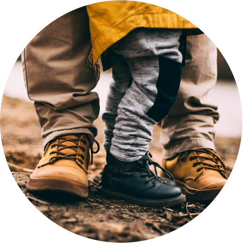 low shot of a son standing in between a father's feet