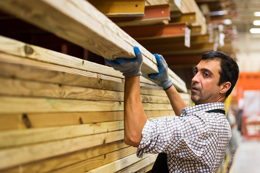 Worker taking lumber off shelf in home improvement store