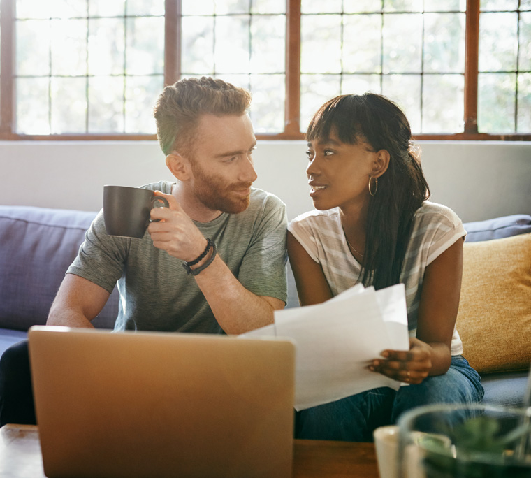 couple reviewing finances, couple on couch, couple looking at eachother