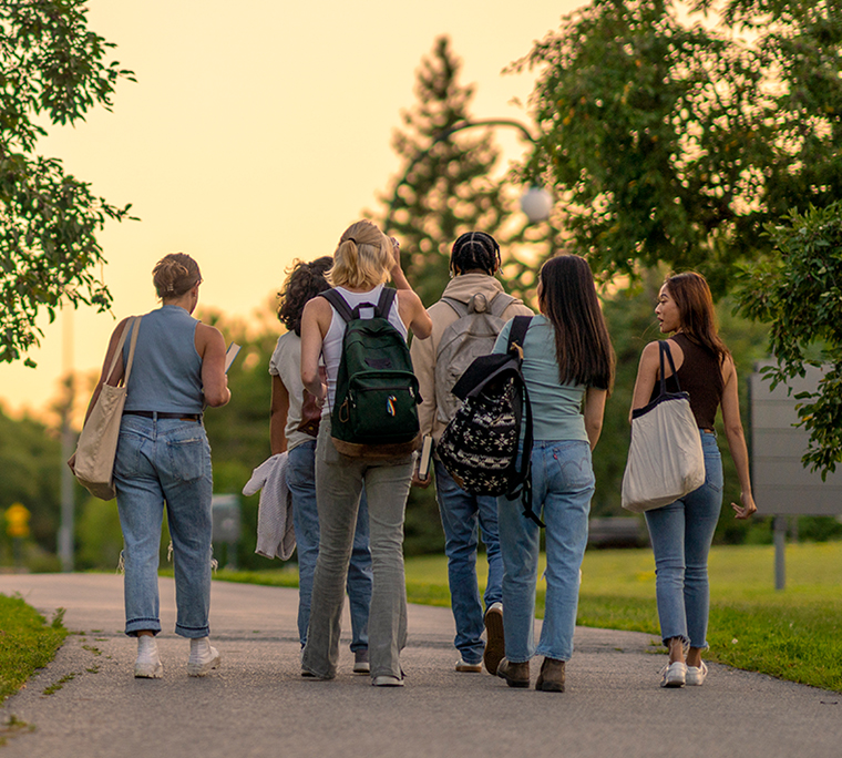 Students walking down a pathway through a park.