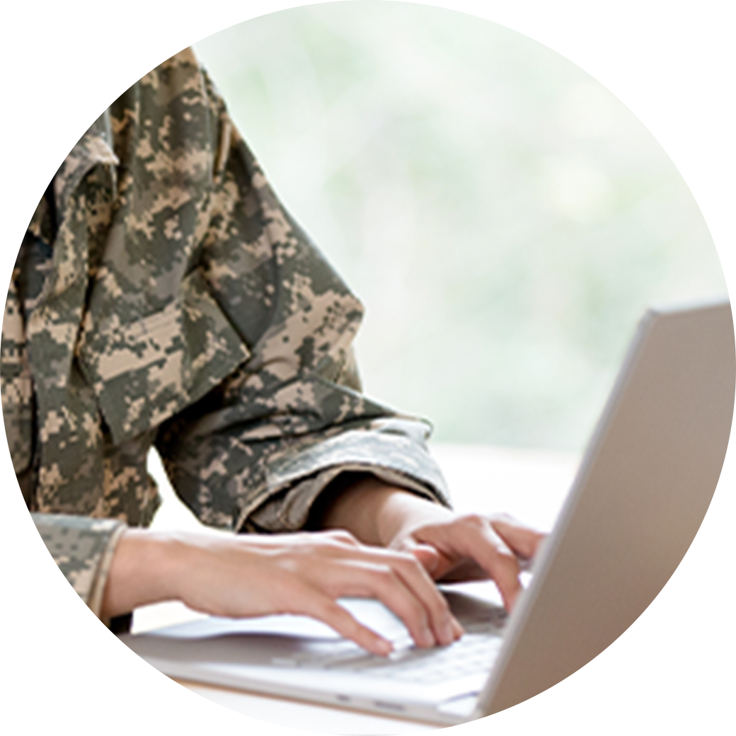 Person typing on a laptop wearing a military jacket
