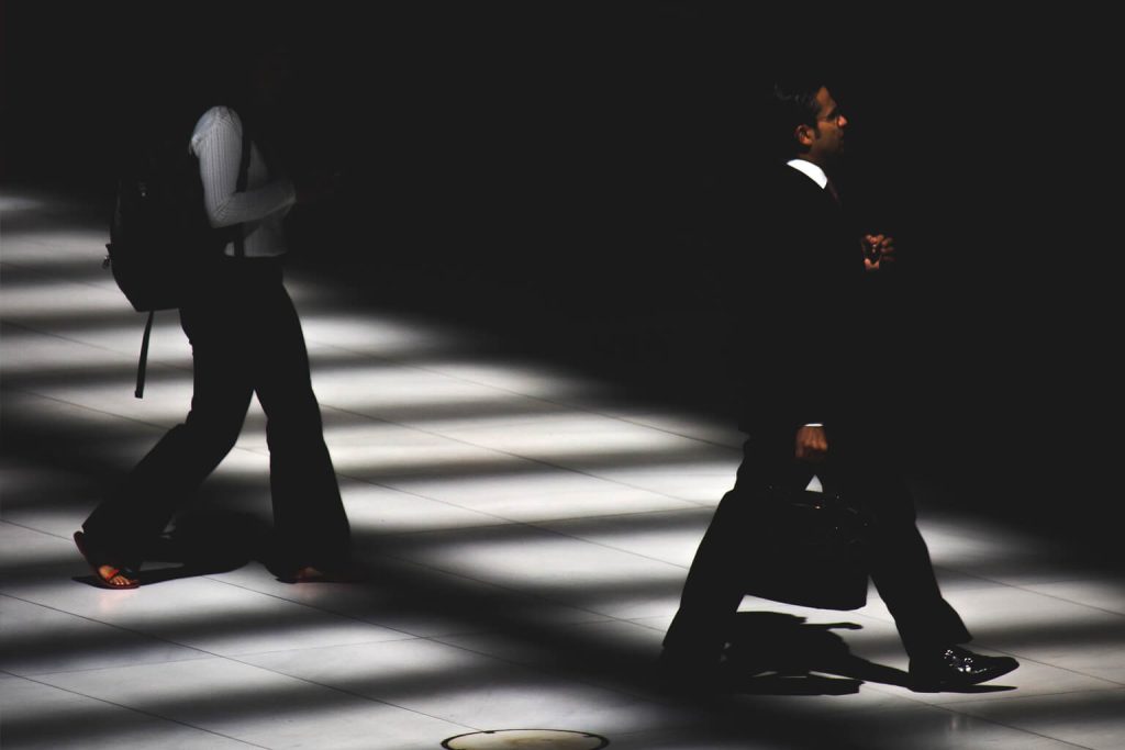 Two people walking across a dark hall