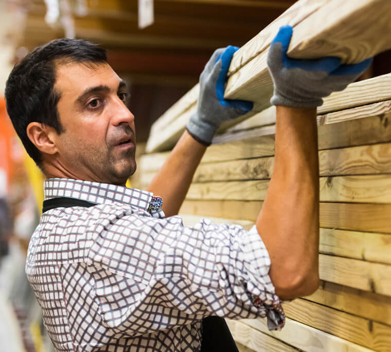 Worker in home improvement shop lifting lumber off a shelf