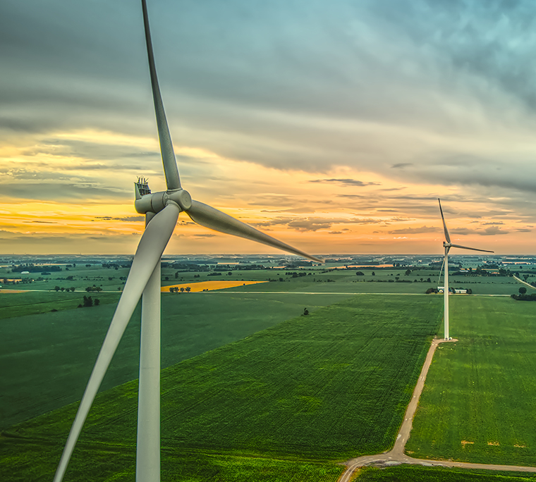 Aerial image of two wind turbines in rural farmland at sunset in Ontario, Canada