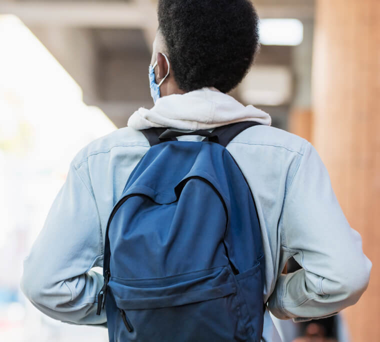 Back view of student wearing backpack at school