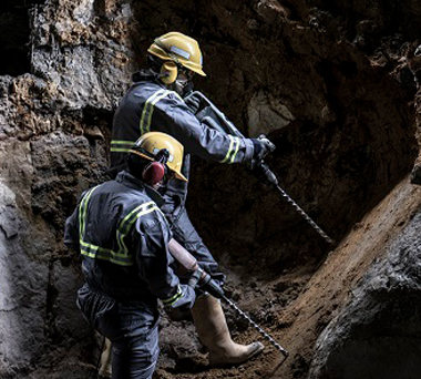 Two miners with drills in a mine