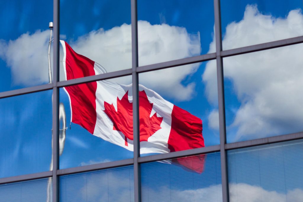 Canadian flag reflected in a glass office building