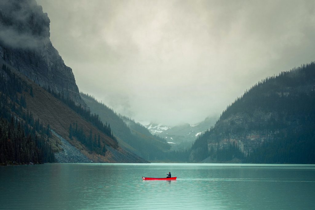 Single canoist paddling on a lake surrounded my mountains