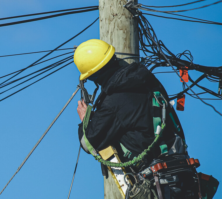 Worker repairing lines on telephone pole