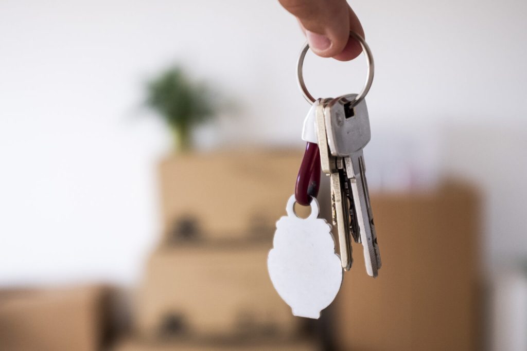 Fingers holding a set of keys in front of packed boxes