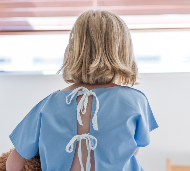 a child is in a hospital gown with her back facing the camera