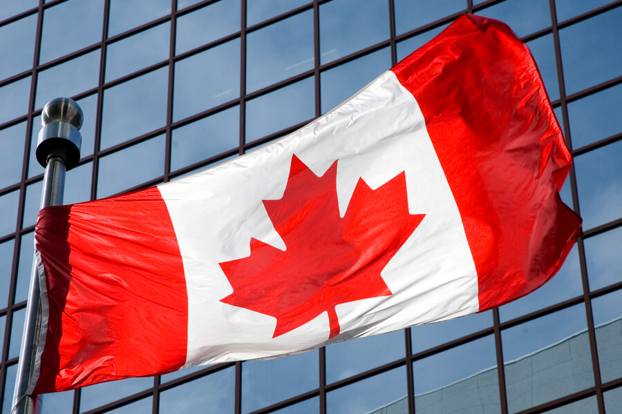 Canadian flag in front of glass office building