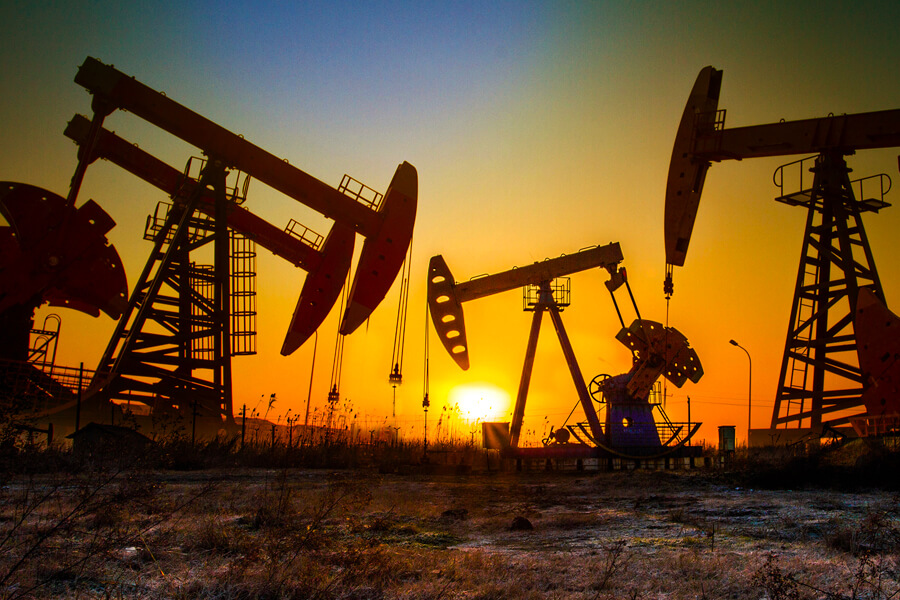 Pump jacks in oil field at sunset