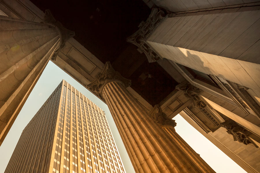 Looking up a skyscraper from between a bank's columns