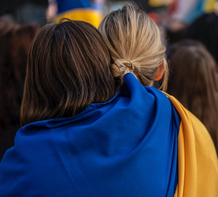 Two people hugging while wrapped in a Ukrainian flag