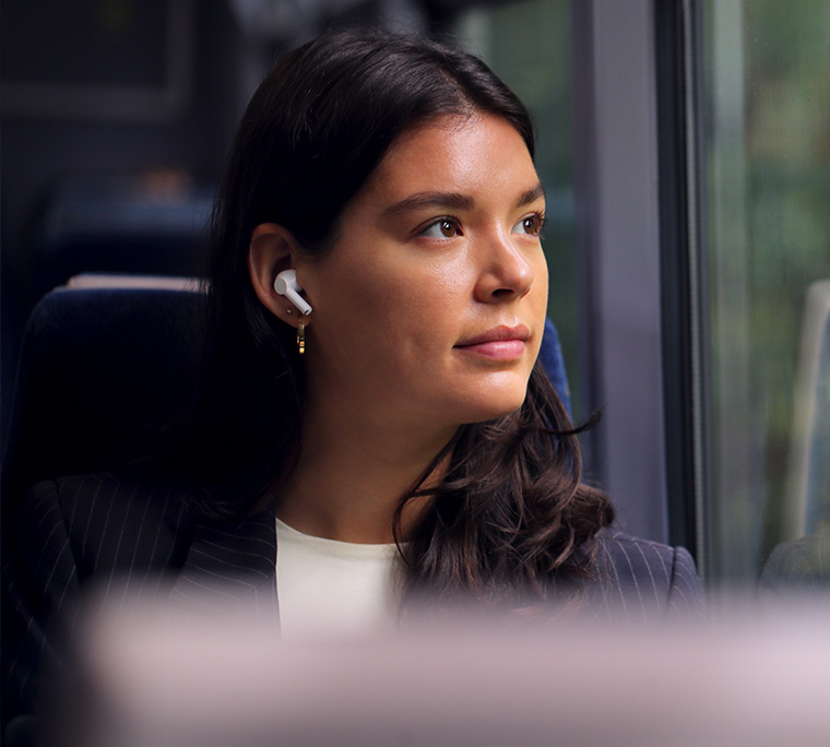 a young woman with headphones on on the bus gazes out the window